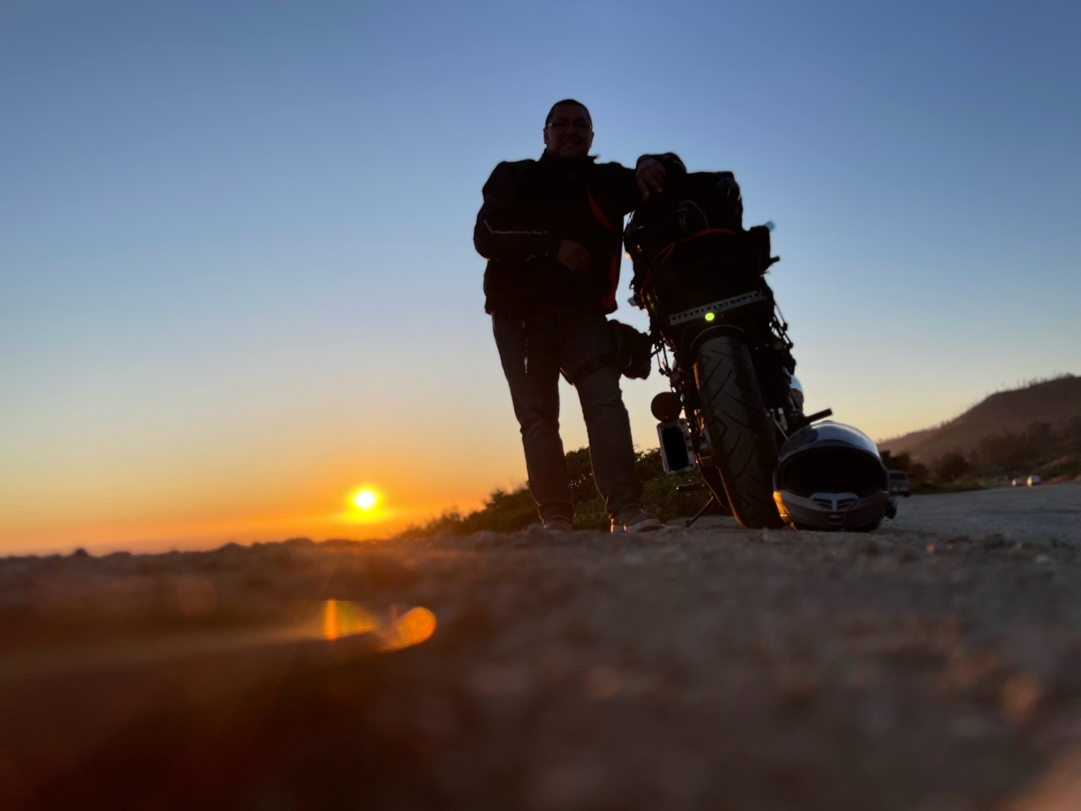 Gabe standing next to his 750cc Honda Shadow motorcylce with the sun setting in the background.